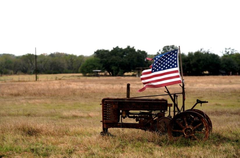 FILE PHOTO: A tattered U.S. flag flies on an old tractor in a farm field outside Sutherland Springs,Texas, U.S. November 8, 2017. Reuters/Rick Wilking