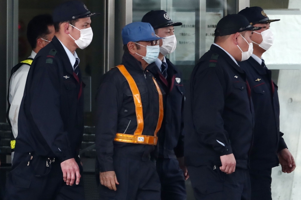  In this file photo taken on March 6, 2019, former Nissan chairman Carlos Ghosn (C-light blue cap) is escorted as he walks out of the Tokyo Detention House following his release on bail in Tokyo. / AFP / Behrouz MEHRI
 
