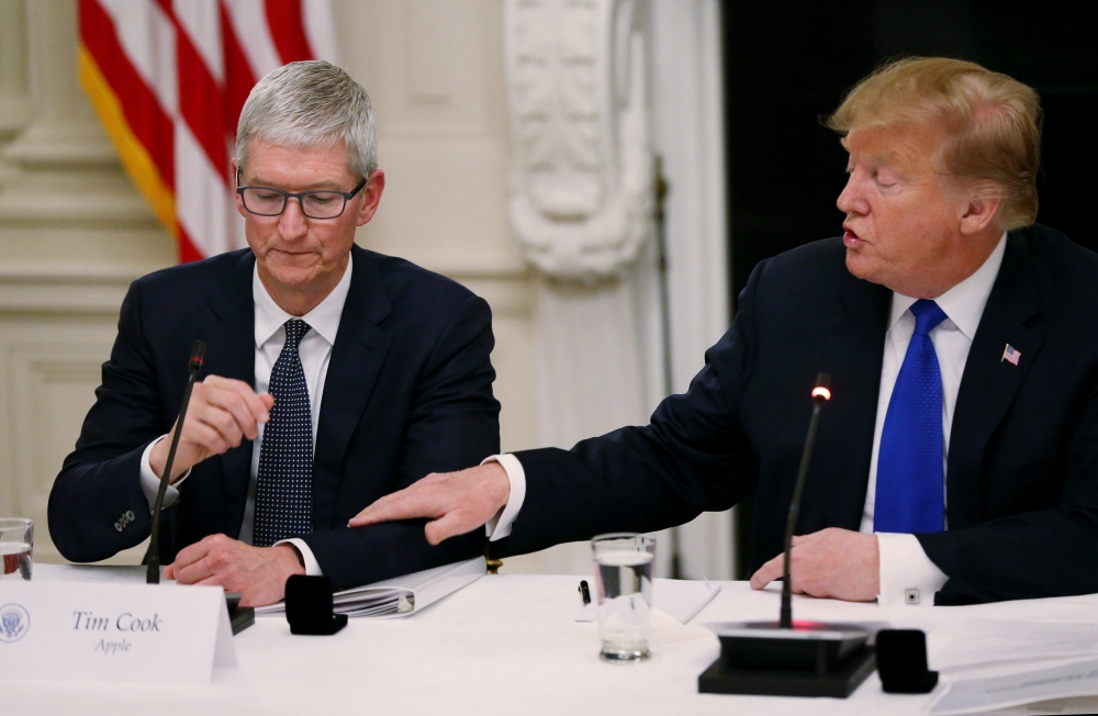 US President Donald Trump reaches out to Apple CEO Tim Cook as they participate in an American Workforce Policy Advisory Board meeting in the White House State Dining Room, March 6, 2019. Reuters/Leah Millis