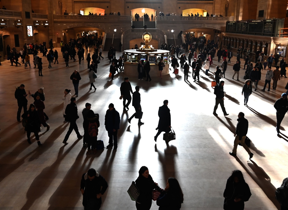 Commuters walk through the morning bright sunlight coming from the 60 feet (18m) high windows in Grand Central Terminal in New York City on March 11, 2019 the first morning after Daylight Savings Time took effect March 10, 2019. AFP / Timothy A Clary 