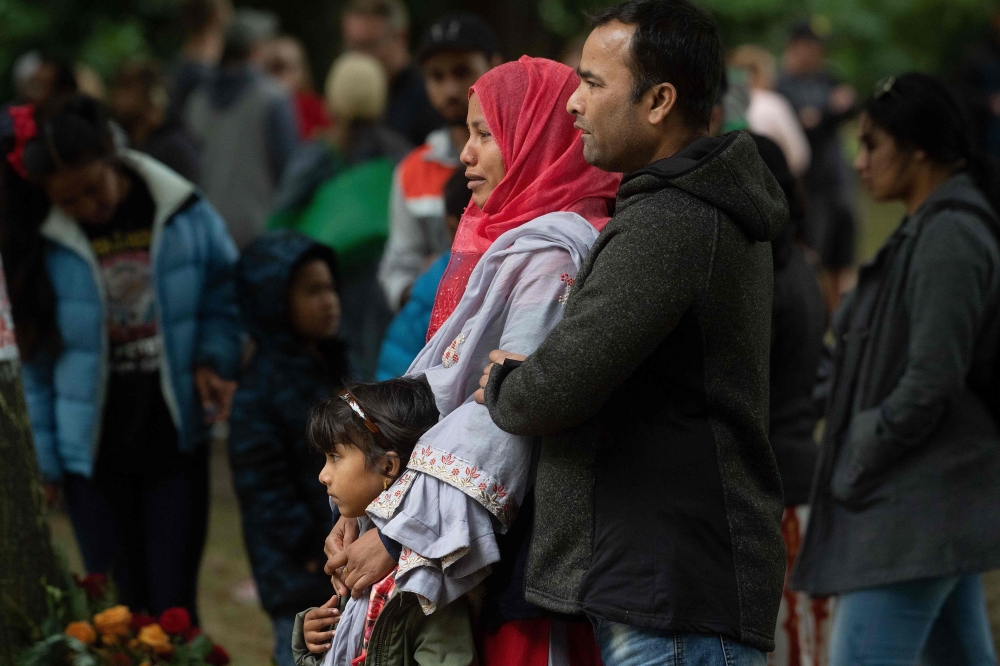 A Muslim family stands across the road from the Dean Street mosque when worshipers were gunned down in Christchurch on March 17, 2019, two days after a shooting incident at two mosques in the city.  AFP / Marty Melville
