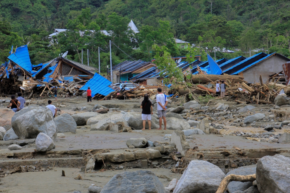 People stand as they look at damaged houses after a flash flood in Sentani, Papua, Indonesia, March 17, 2019 in this photo taken by Antara Foto. Antara Foto/Gusti Tanati/ via REUTERS 