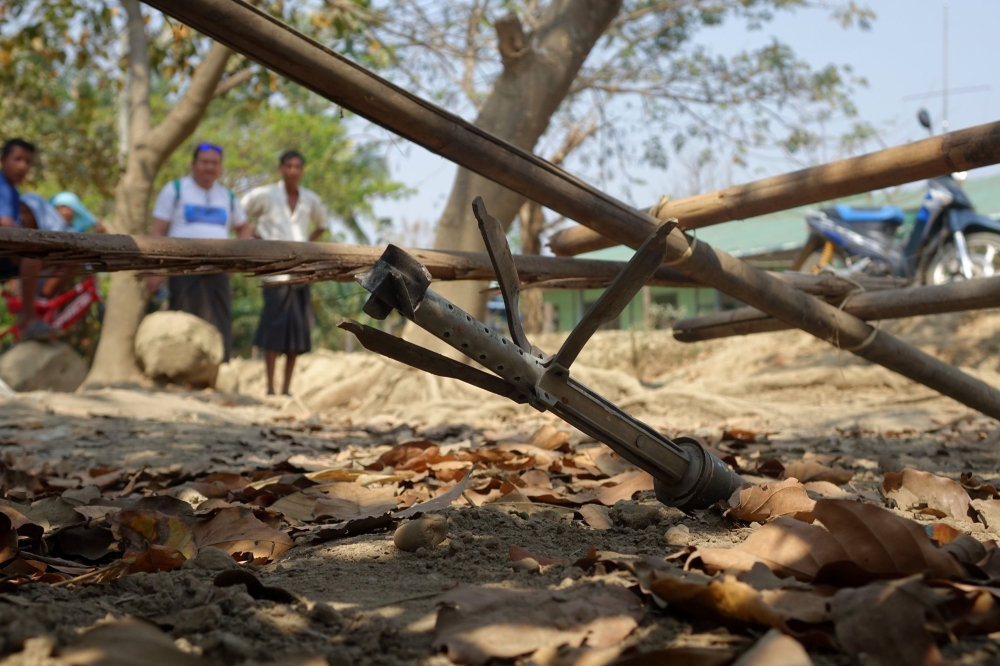 This photo taken on March 16, 2019 shows people looking at an unexploded rocket in the Mrauk U township in Rakhine. / AFP / STR 
