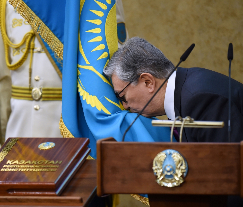 Acting President of Kazakhstan Kassym-Jomart Tokayev kisses a flag as he takes part in a swearing-in ceremony during a joint session of the houses of parliament in Astana, Kazakhstan March 20, 2019. 	
