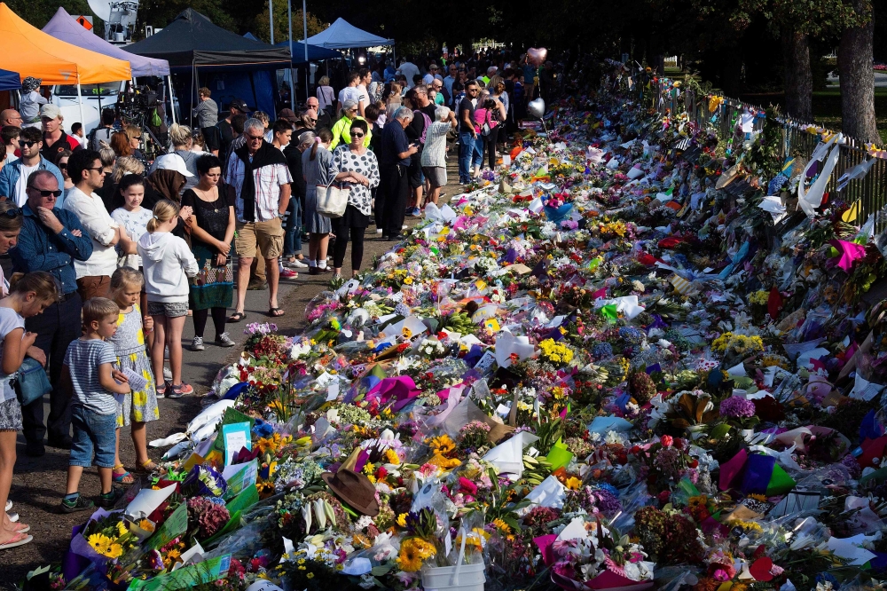 Floral tributes to those who were gunned down at the two mosques are seen against a wall bordering the Botanical Garden in Christchurch on March 19, 2019.   AFP / Marty MELVILLE
