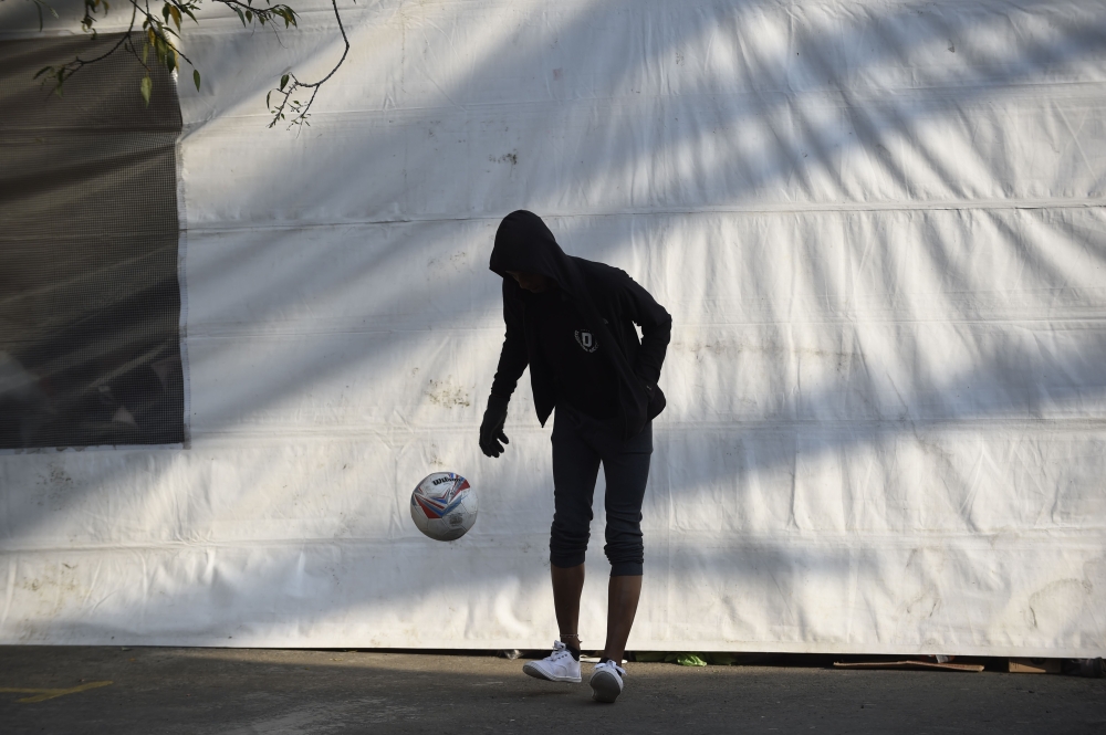 A Central American migrant taking part in a caravan towards the US plays with a ball at a stadium-turned-shelter during a stop in the journey in Mexico City on November 7, 2018. AFP/Alfredo Estrella