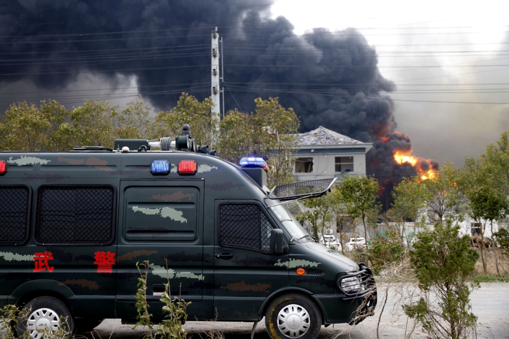 A vehicle of paramilitary police is seen near smoke following an explosion at a chemical industrial park in Xiangshui county, Yancheng, Jiangsu province, China March 21, 2019. REUTERS