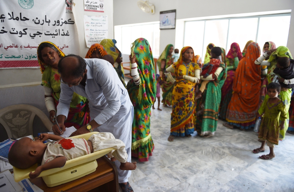 In this picture taken on May 25, 2018, a Pakistani paramedic weighs a child at Mithi Civil Hospital in Mithi, a remote town in southern Pakistan. AFP /Rizwan Tabassum