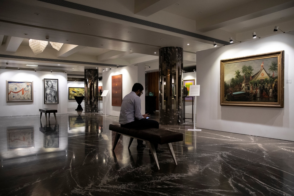 A staff member looks at his phone as artworks once part of billionaire jeweller Nirav Modi's collection are seen on display ahead of their auction at a gallery in Mumbai, India, March 25, 2019. REUTERS/Danish Siddiqui