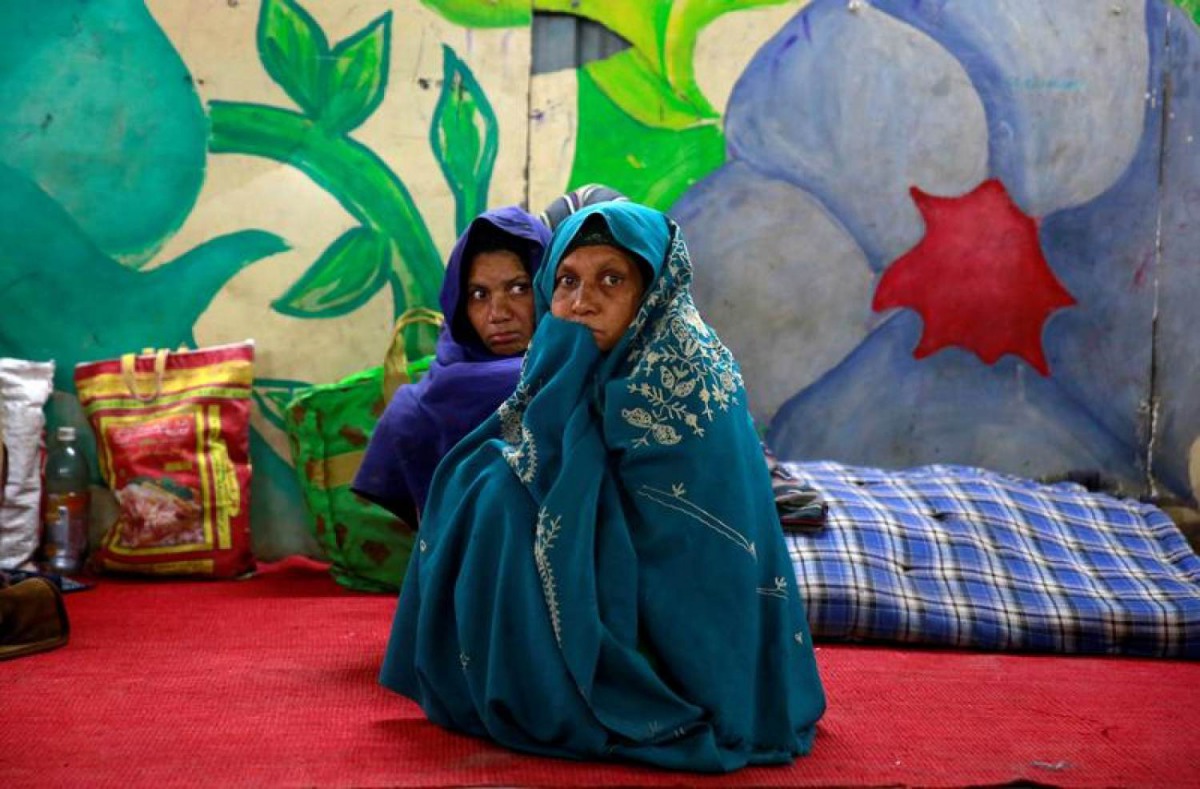 Women wrap themselves in blankets in a government shelter for homeless people to escape the cold in Delhi, India January 16, 2017. Reuters/Cathal McNaughton