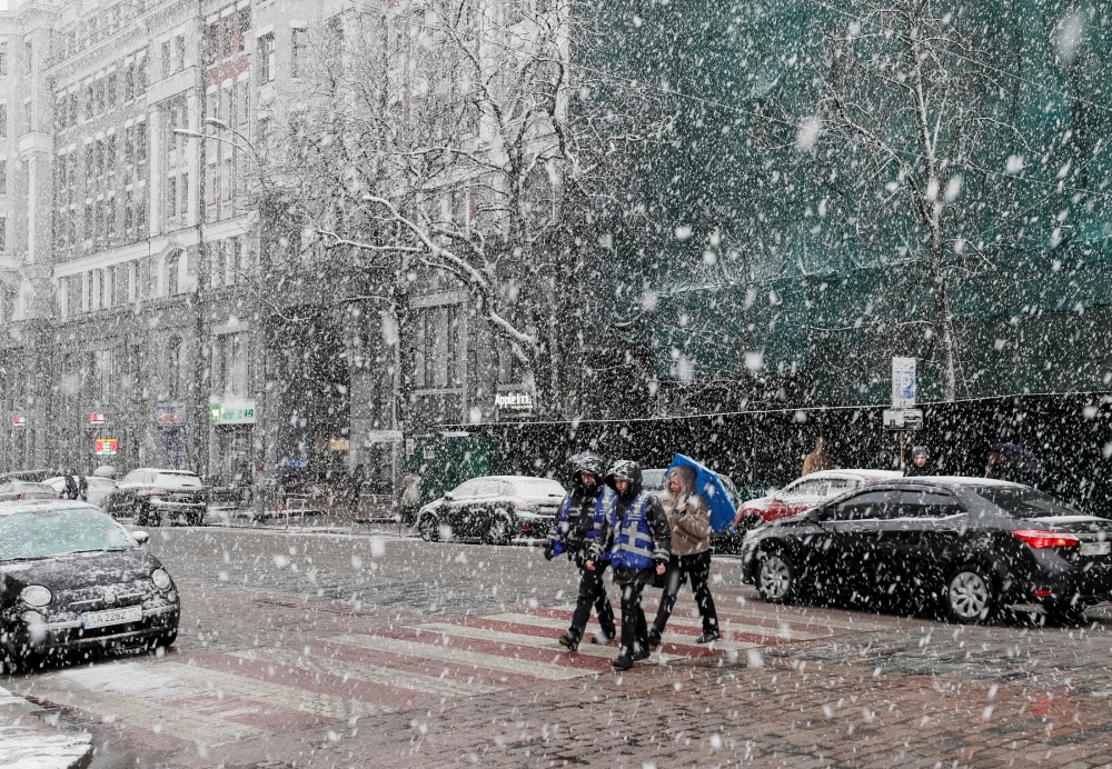 People cross a street amid a snow flurry in central Kiev, Ukraine March 27, 2019. Reuters/Gleb Garanich