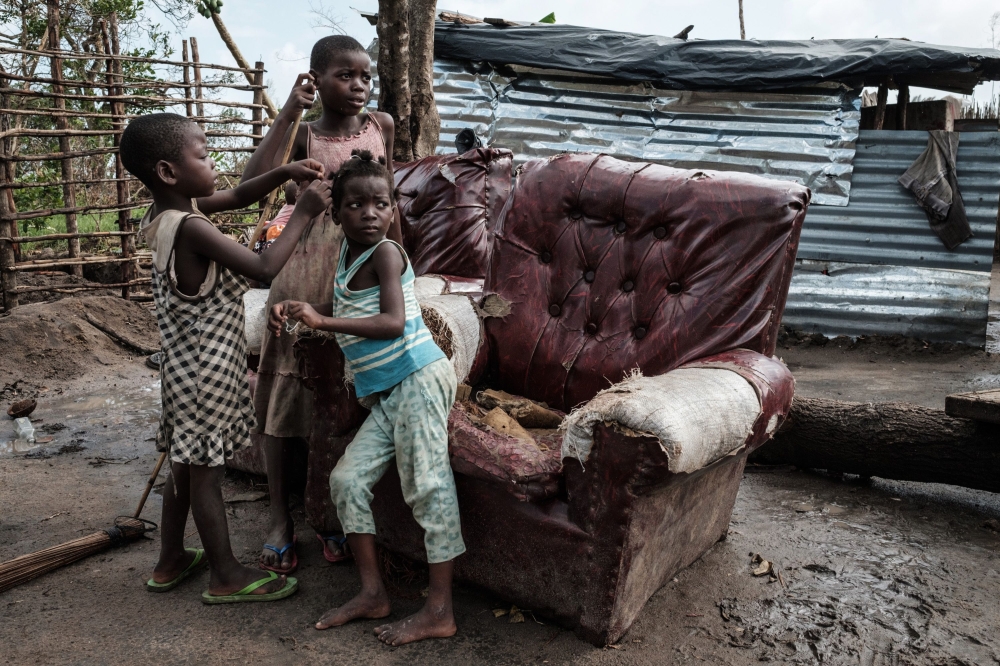 Children play in front of a house destroyed by the winds of cyclone Idai in Beira, Mozambique, on March 27, 2019.  AFP / Yasuyoshi Chiba  