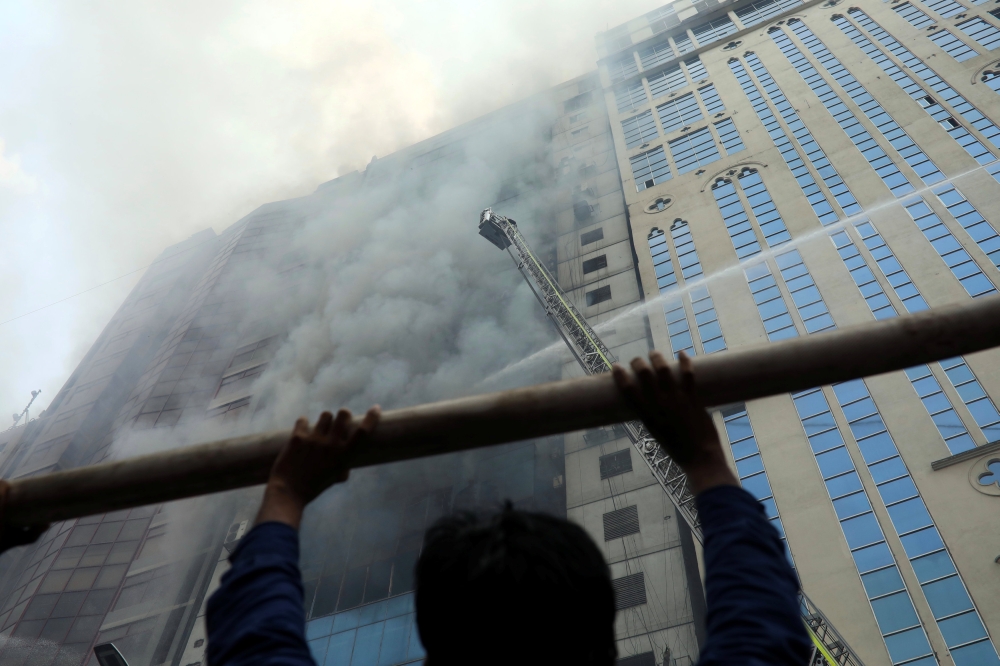 A person looks on as firefighters attempt to extinguish a fire at a multi-storey commercial building in Dhaka, Bangladesh, March 28, 2019. REUTERS/Mohammad Ponir Hossain