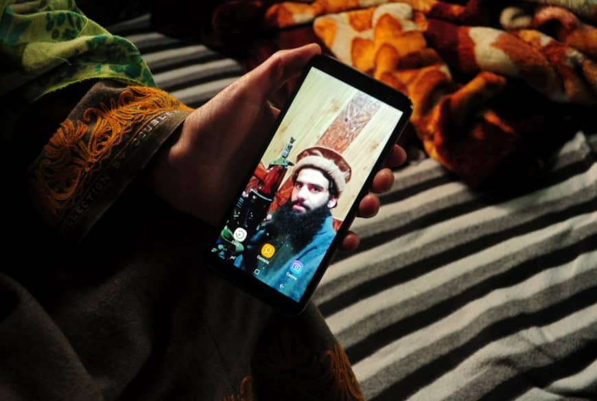 A sister of suspected militant Owais Malik shows a picture of him on her phone at her home in Kashmir's Kulgam district on Feb. 16. Reuters