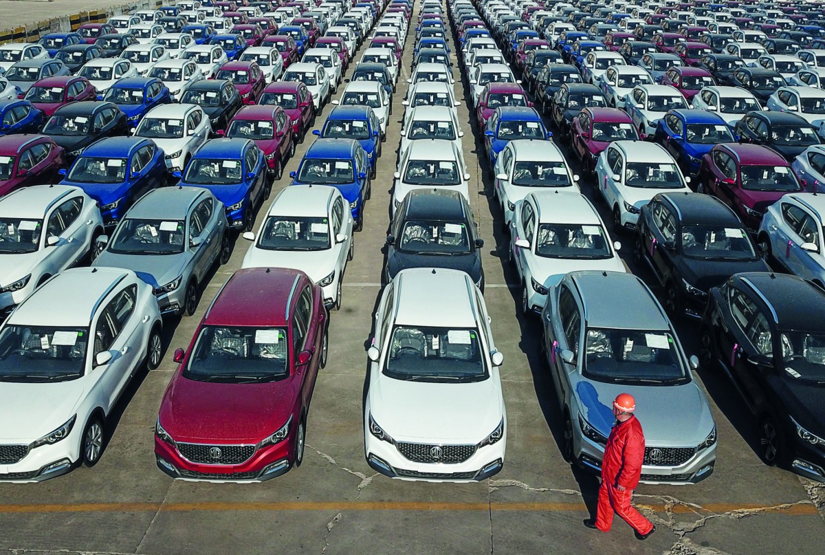 A staff member walks past new cars waiting to be exported at a port in Lianyungang in China's eastern Jiangsu province on March 31, 2019. AFP