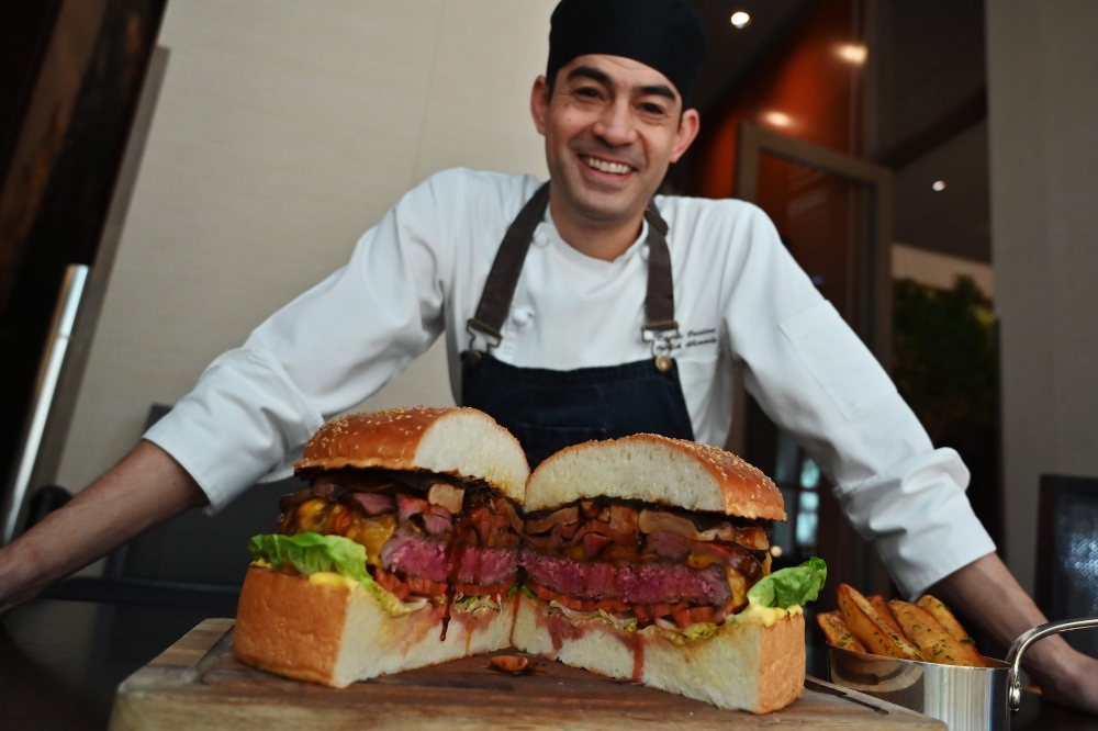 Patrick Shimada, the chef de cuisine at The Oak Door of the Grand Hyatt Tokyo hotel poses with a 3kgs burger in Tokyo on April 1, 2019.  AFP / Charly Triballeau 