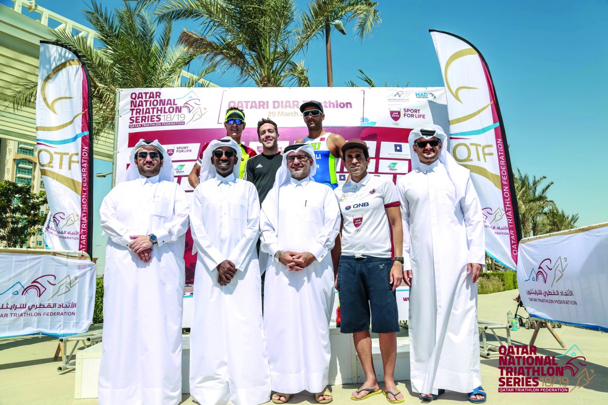 The podium winners at the Qatari Diar Triathlon pose for a picture with officials of Qatar Cycling and Triathlon Federation at  Lusail City. 