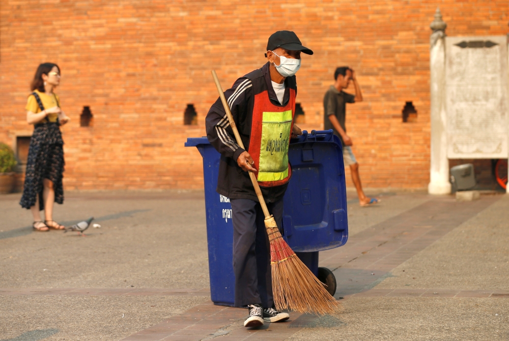 A man wears mask as he sweeps the ground near a palace in Chiang Mai, Thailand April 3, 2019. Reuters/Soe Zeya Tun