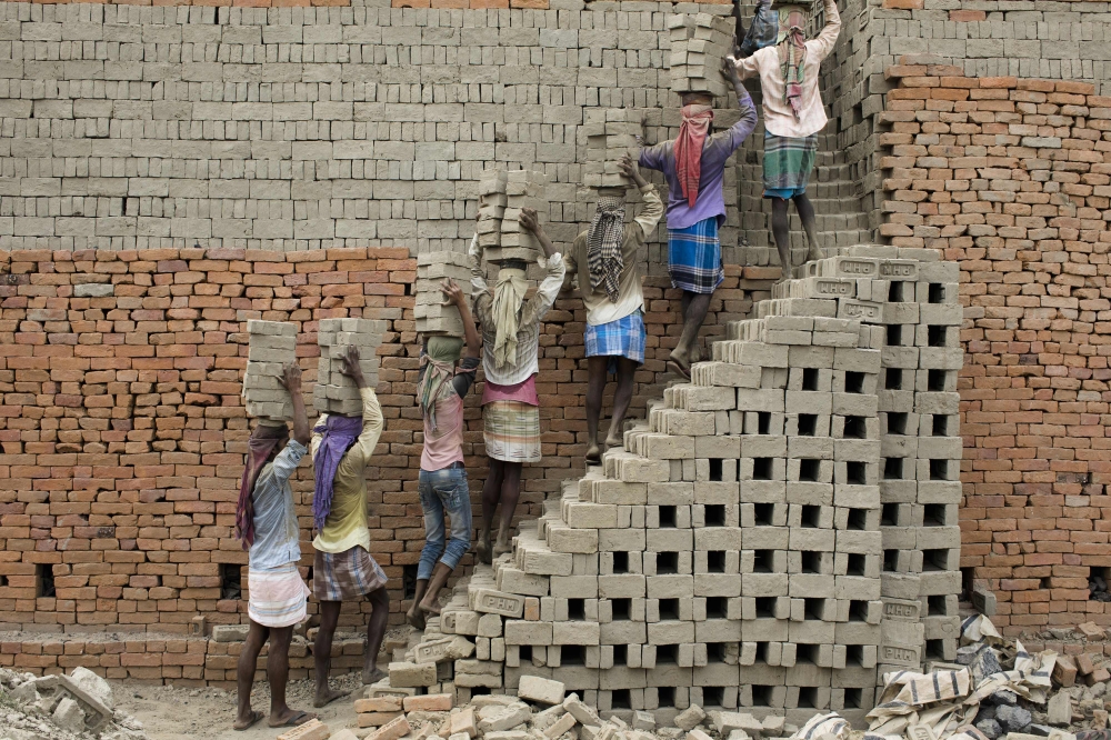 Indian labourers carry clay bricks to a brick kiln in Farakka, in the Indian state of West Bengal, on March 3, 2019.  AFP / Xavier Galiana 
 