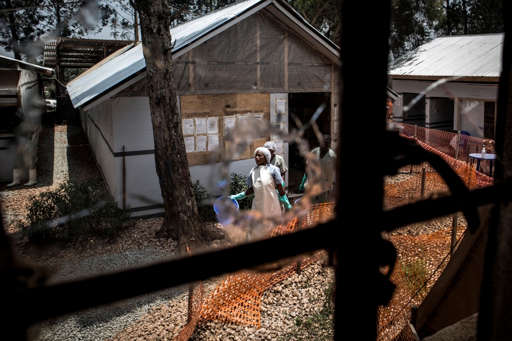 In this file photo taken on March 9, 2019 health workers are seen through a bullet hole left in the window of an Ebola treatment centre, which was attacked in the early hours of the morning in Butembo. AFP / John Wessels
 