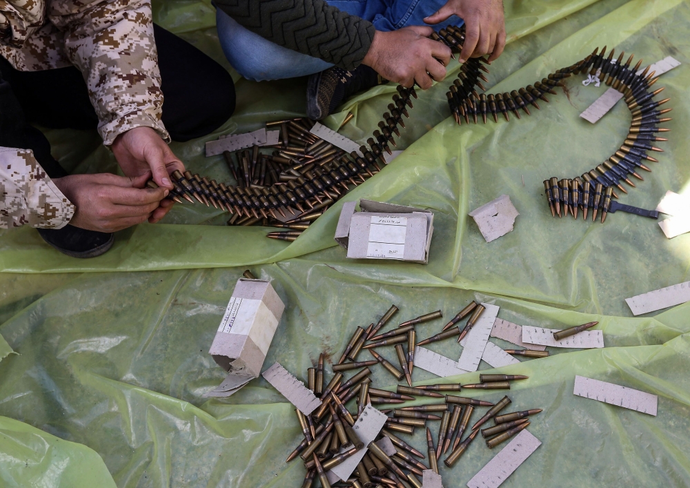 Men load ammunition belts at a position held by forces loyal to Libya's Government of National Accord (GNA) in the suburb of Wadi Rabie about 30 kilometres south of the capital Tripoli on April 12, 2019. AFP / Mahmud Turkia 