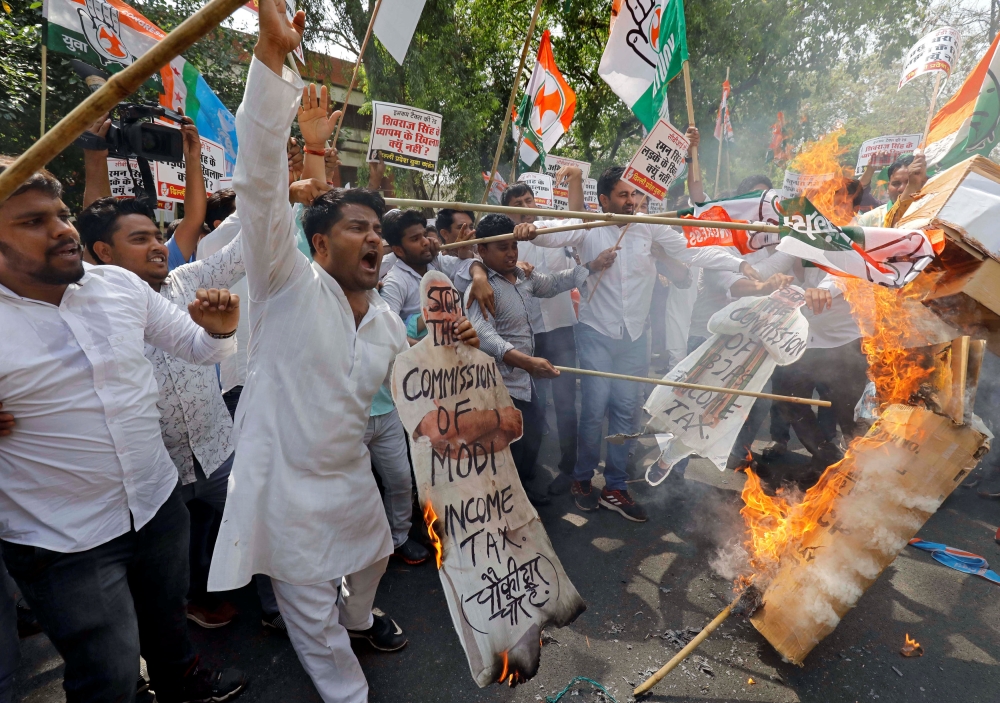 Activists of Delhi Pradesh Youth Congress burn cut-outs of India's Prime Minister Narendra Modi and Chief of India's ruling Bharatiya Janata Party (BJP) Amit Shah during a protest against what they say are politically motivated raids by Income Tax officia