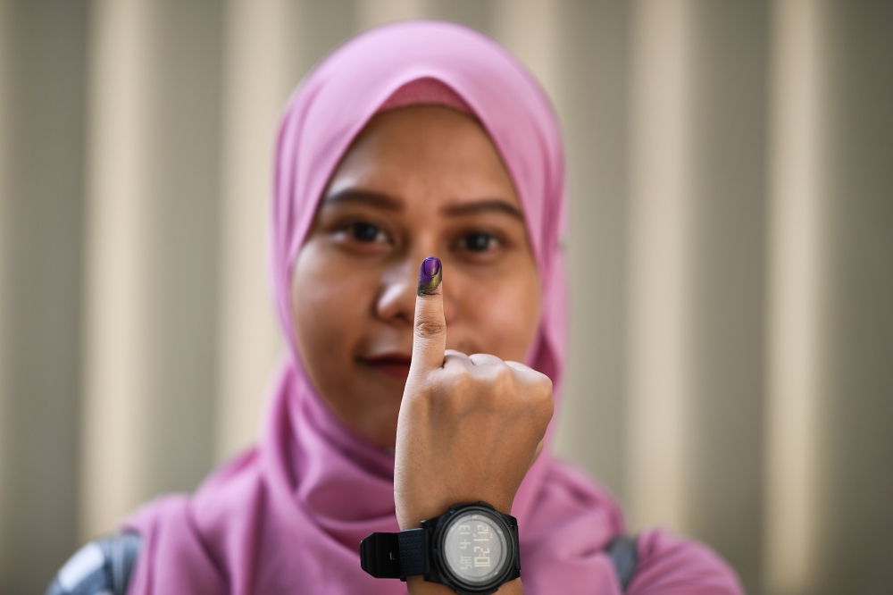 An Indonesian woman, living in Malaysia, shows her inked finger after casting her overseas ballot in their embassy ahead of the country's April 17 general election, in Kuala Lumpur on April 14, 2019. / AFP / Mohd RASFAN 