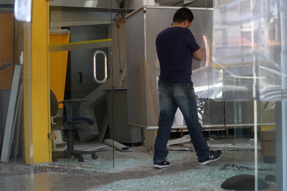 An employee walks next to broken glass at a damaged branch of Banco do Brasil after a gang caused an explosion in a part of the bank in an attempted robbery, in Guararema, near Sao Paulo, Brazil April 4, 2019. Reuters/Amanda Perobelli
