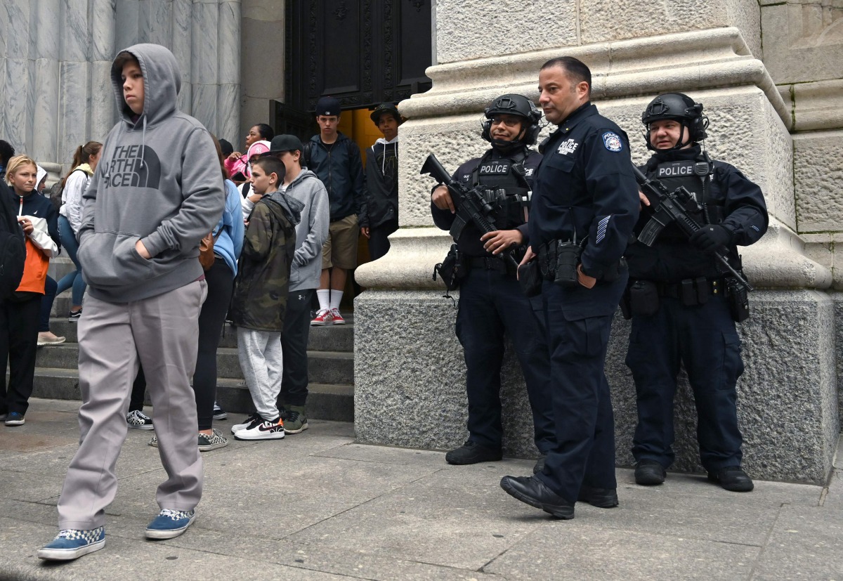 Members of the New York Police Department gather outside St. Patrick's Cathedral on 5th Avenue April 18, 2019, the morning after a man was arrested after trying to enter the Cathedral with gas cans. AFP / Timothy A Clary 