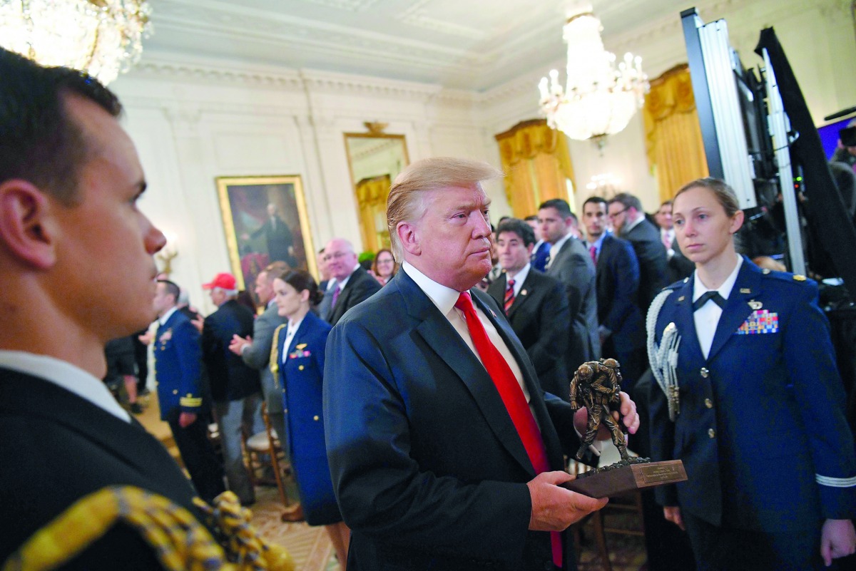 US President Donald Trump departs with a statuette after speaking at an event honoring the Wounded Warrior Project Soldier Ride in the East Room of the White House in Washington, DC on April 18, 2019. AFP / Mandel Ngan

