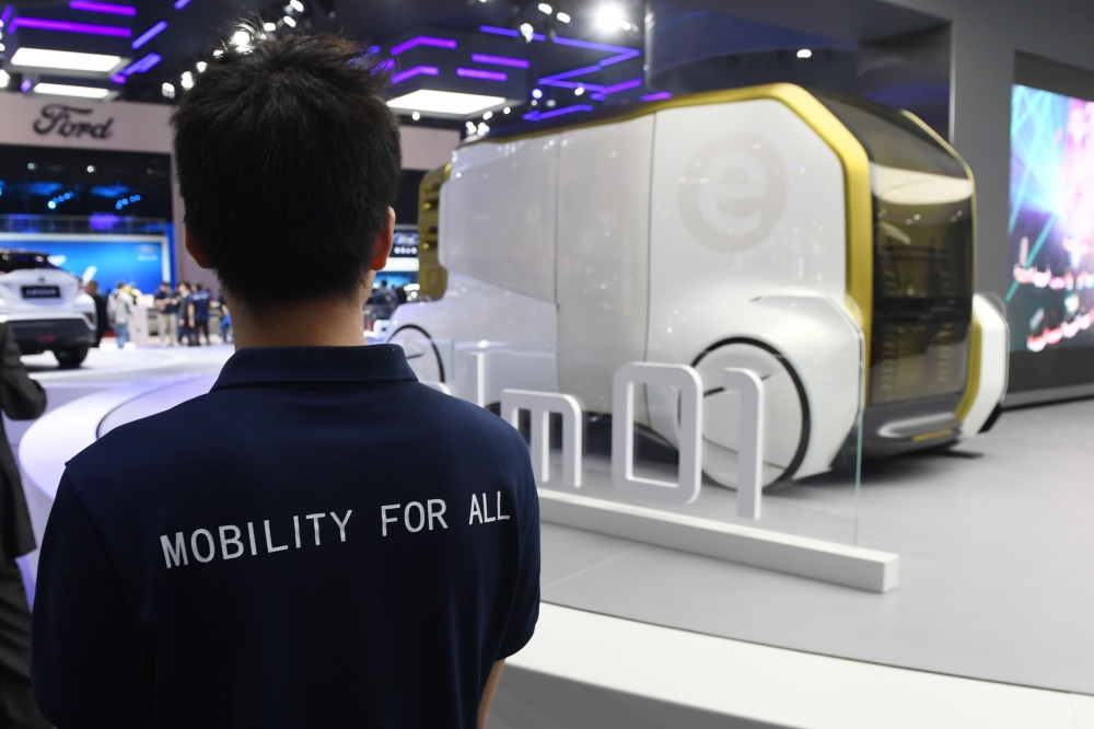 This photo taken on April 17, 2019 shows a Toyota staff member looking at a Toyota e-Calm 01 autonomous vehicle at the Shanghai Auto Show in Shanghai. AFP / Greg Baker