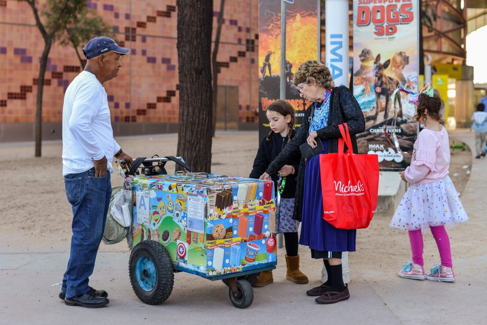 A woman buys ice cream from a vendor outside the California Science Center at Exposition Park in Los Angeles on March 24, 2019.  AFP / Agustin Paullier 