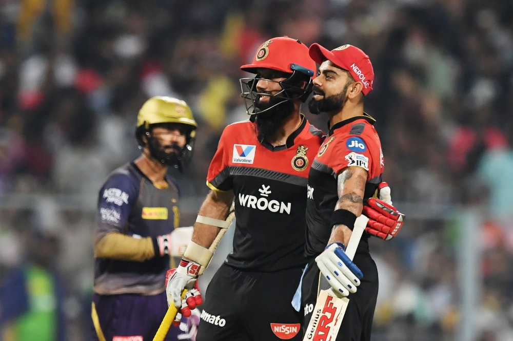 Royal Challengers Bangalore's cricketers Moeen Ali and Virat Kohli (R) celebrate as Kolkata Knight Riders's captain Dinesh Karthik(L) looks on during the 2019 Indian Premier League (IPL) Twenty 20 cricket match between Kolkata Knight Riders and Royal Chal