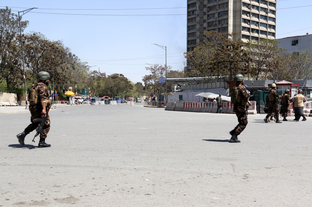 Afghan security personnel stand guard near the Afghan communication ministry as an attack between Afghan forces and attackers is still going on in central Kabul on April 20, 2019.   AFP / STR