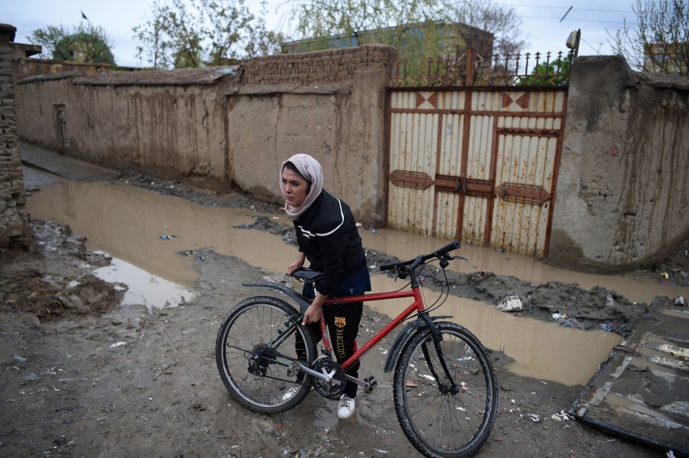 Afghan cyclist Kobra Samim adjusts her bicycle on a street in Kabul. / AFP / Wakil Kohsar 