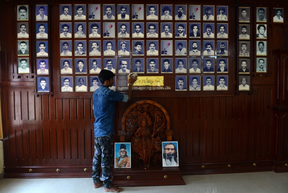In this photo taken on April 20, 2019, a worker dusts memorial portraits of party workers killed in political violence hanging at the Rashtriya Swayamsevak Sangh (RSS) office at Thalaserry in the southern Indian state of Kerala. BHUVAN BAGGA / AFP / ARUN 
