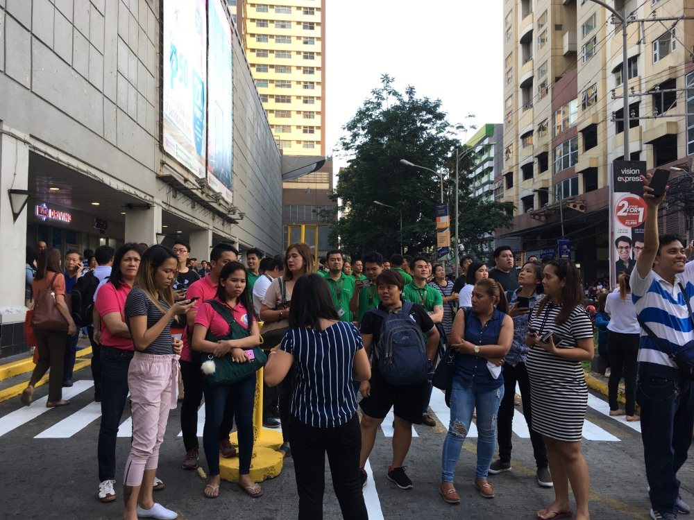 People gather outside a shopping mall after a powerful earthquake rocked Manila on April 22, 2019.  AFP / Ted ALJIBE