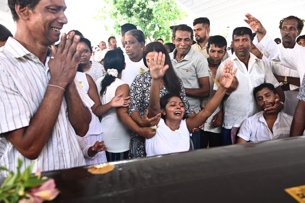 Relatives mourn beside a coffin of a bomb blast victim during a funeral service at St Sebastian's Church in Negombo on April 23, 2019, two days after a series of bomb attacks targeting churches and luxury hotels in Sri Lanka. AFP / Jewel SAMAD
