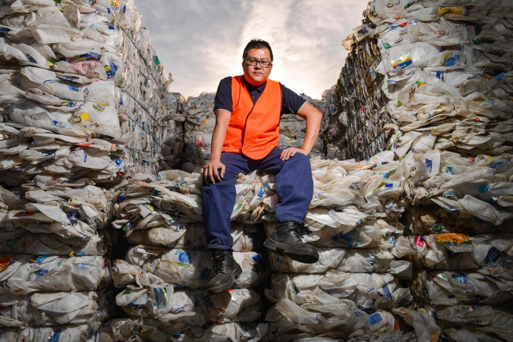Northern Adelaide Waste Management Authority supervisor Thao Nguyen posing amongst recycled plastic bottles at the recycling site in Edinburgh, near Adelaide, on April 17, 2019.  AFP / Brenton Edwards