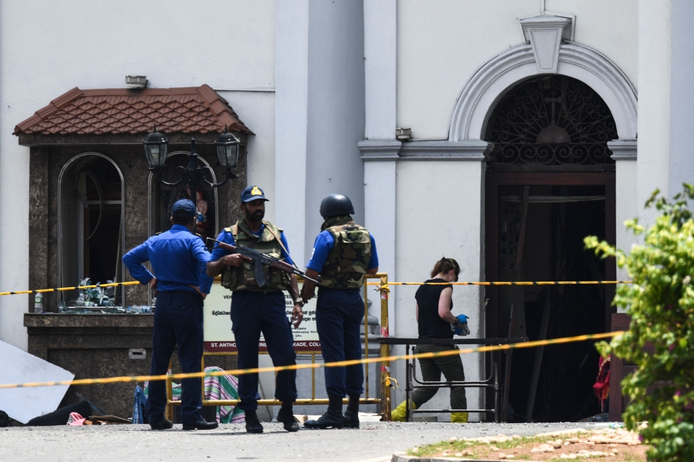 A foreign investigator (R) walks into St. Anthony's Shrine as soldiers stand guard in Colombo on April 25, 2019, following a series of bomb blasts targeting churches and luxury hotels on the Easter Sunday in Sri Lanka. AFP / Jewel Samad