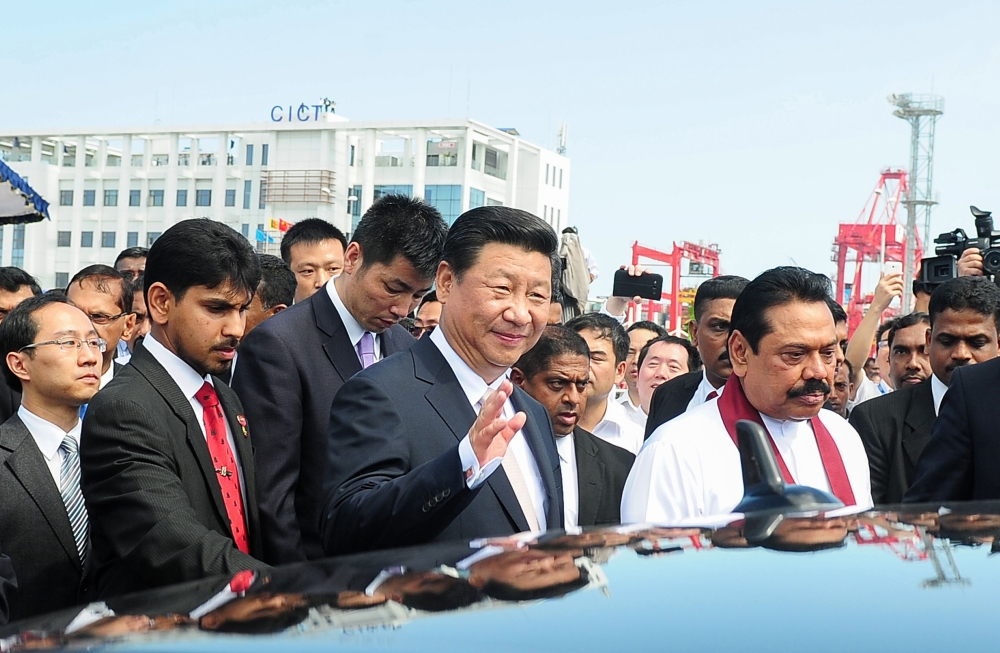 In this file photo taken on September 17, 2014, Chinese President Xi Jinping (C) waves as he leaves alongside Sri Lanka's then-president Mahinda Rajapaksa (R) after formally opening the start of work on the Chinese-funded Port City on reclaimed land in Co