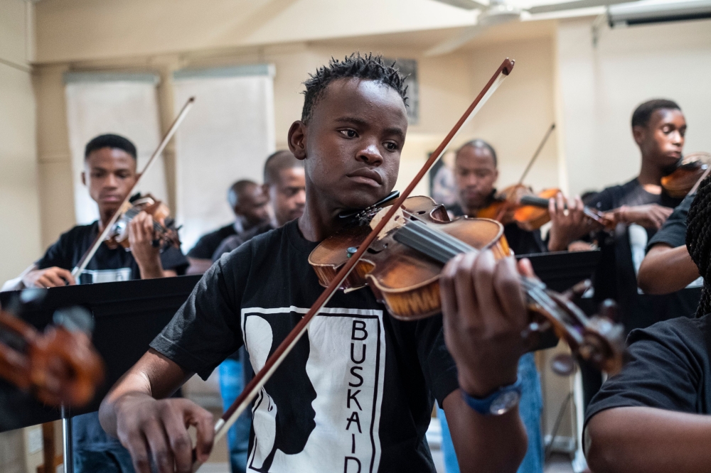 Xolani Zingeni (C), 16, plays with young students and orchestra members from Buskaid during a practice of the South African national Anthem, ahead of a performance for a grant application, at the Reformed Presbyterian Church in Diepkloof, Soweto, on April