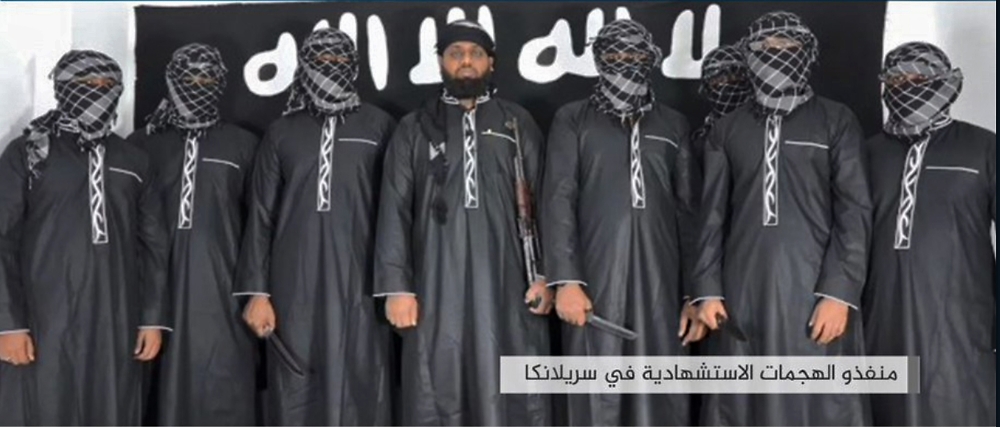 An image grab taken from a press release issued on April 23, 2019 by the Islamic State (IS) group's propaganda agency Amaq, allegedly shows eight men it said carried out a string of deadly suicide bomb blasts on Easter Sunday in Sri Lanka, lined up at an 