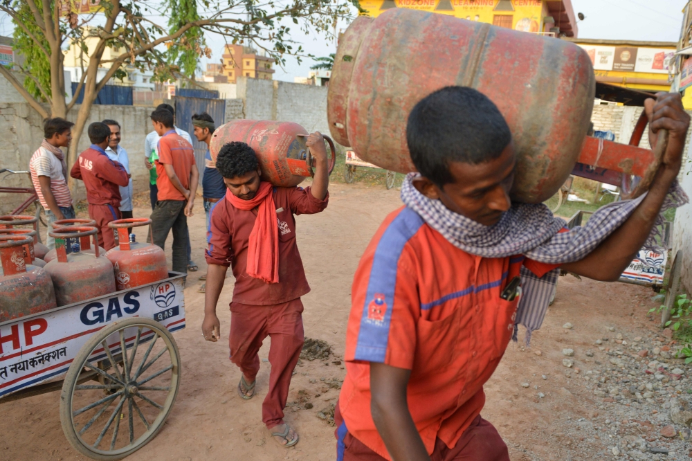 In this photograph taken on April 9, 2019, Indian liquid petroleum gas (LPG) vendors carry gas cylinders at a distribution centre in Patna. AFP / NARINDER NANU 
