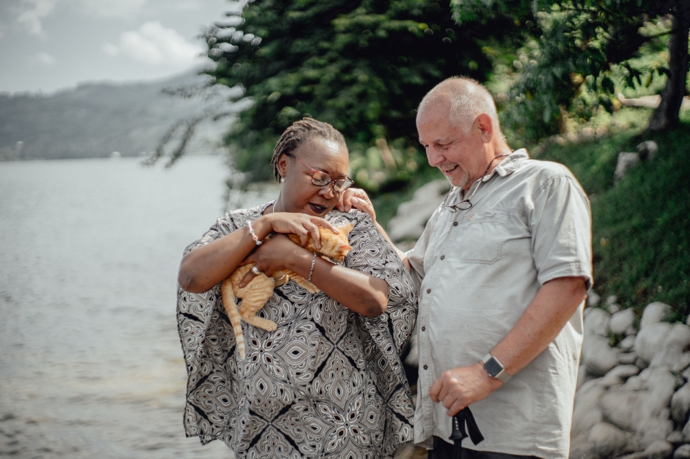 Esperance Mawanzo and Luc Henkinbrant, founders of the Esperance (Hope) Agency, play with a cat as they stand in front of their ecotourism lodge on Idjwi island, in Lake Kivu, on April 5, 2019.  AFP / Luke Dennison 