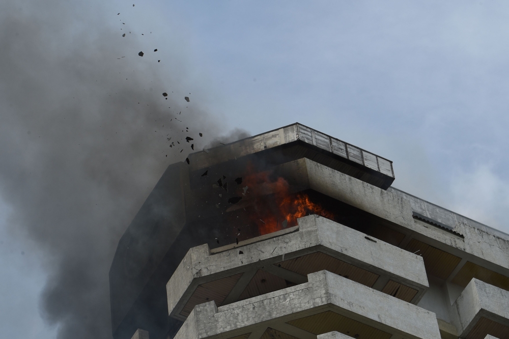Flames and debris fly out from a burning 23-storey residential building in Paranaque City in suburban Manila on April 29, 2019. According to local media reports, six people were injured in the incident, with no deaths reported so far. / AFP / Ted Aljibe 