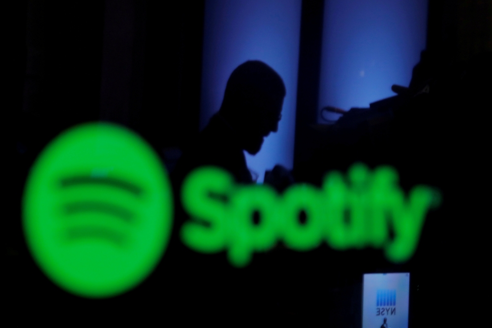 FILE PHOTO: A trader is reflected in a computer screen displaying the Spotify brand before the company begins selling as a direct listing on the floor of the New York Stock Exchange in New York, U.S., April 3, 2018. REUTERS/Lucas Jackson/File Photo