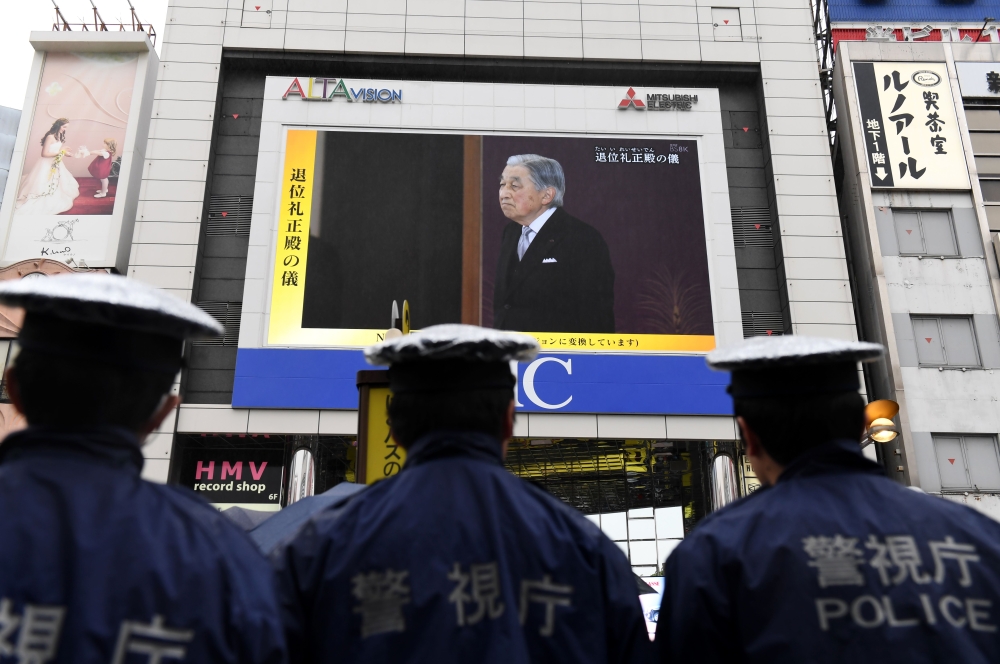 Japanese policemen stand guard as they look at a screen displaying live news of Japanese Emperor Akihito's abdication ceremony in Tokyo on April 30, 2019. AFP / Toshifumi KITAMURA