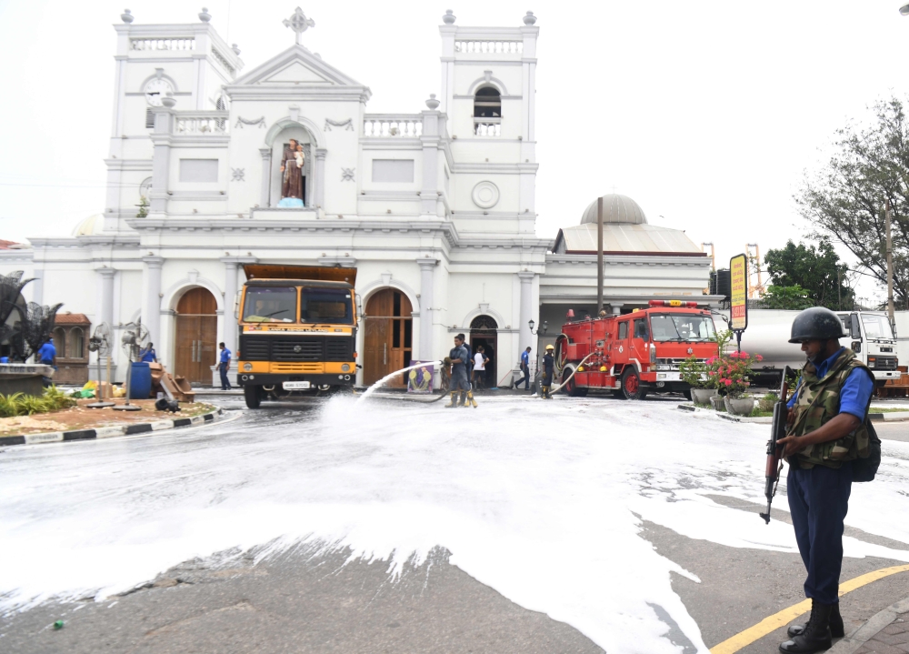 Sri Lankan navy soldiers clean St. Anthony's Shrine while a security personnel stands guard in Colombo on April 27, 2019, following a series of bomb blasts targeting churches and luxury hotels on Easter Sunday in Sri Lanka. / AFP / LAKRUWAN WANNIARACHCHI