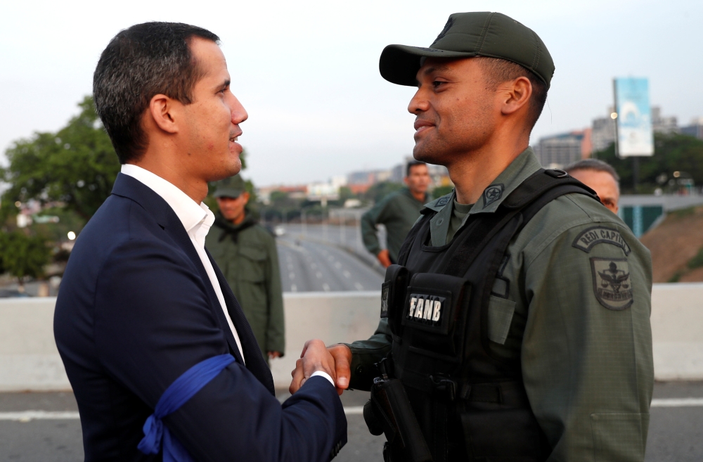 Venezuelan opposition leader Juan Guaido, who many nations have recognised as the country's rightful interim ruler, shakes hands with a military member near the Generalisimo Francisco de Miranda Airbase 